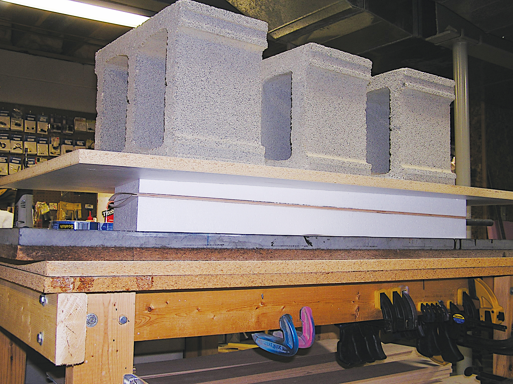 Cinder blocks stacked on a wooden workbench in a workshop.