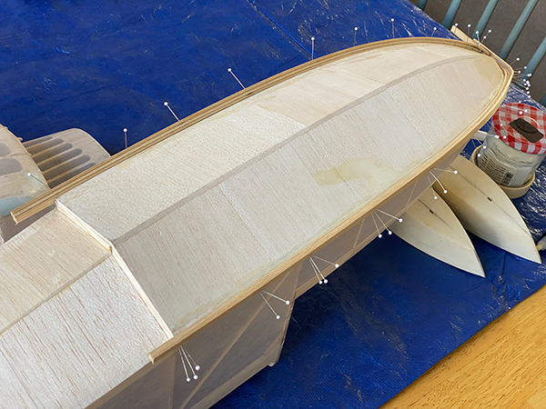 Model boat under construction on blue surface.