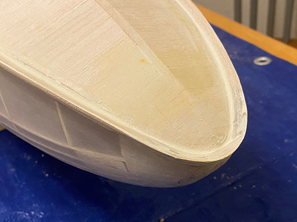 Wooden boat model on a blue surface.