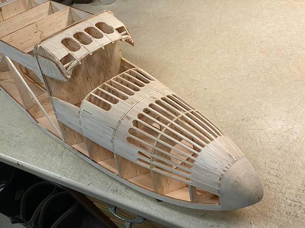 Wooden airplane model under construction on a workbench.