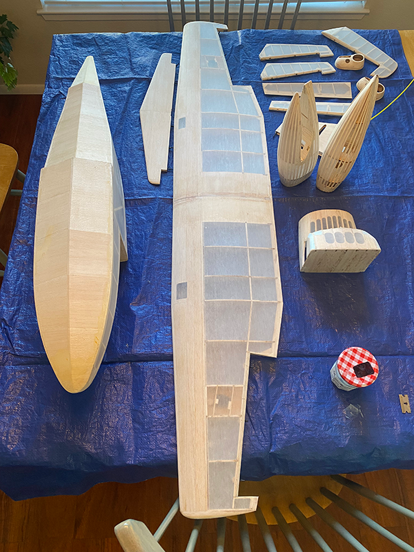 Wooden model ship parts on a blue tablecloth.