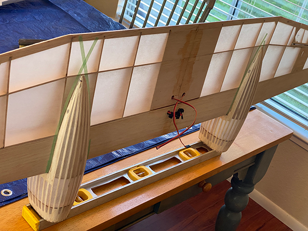 Wooden model airplane wing under construction on a table.