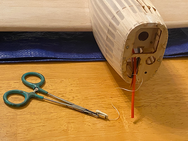 Model airplane fuselage and green-handled scissors on a wooden table.