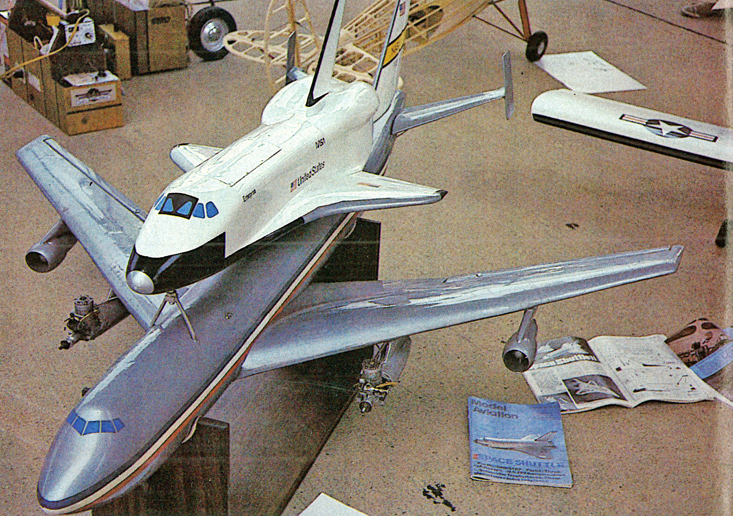Space shuttle model on a Boeing 747 model in a workshop.