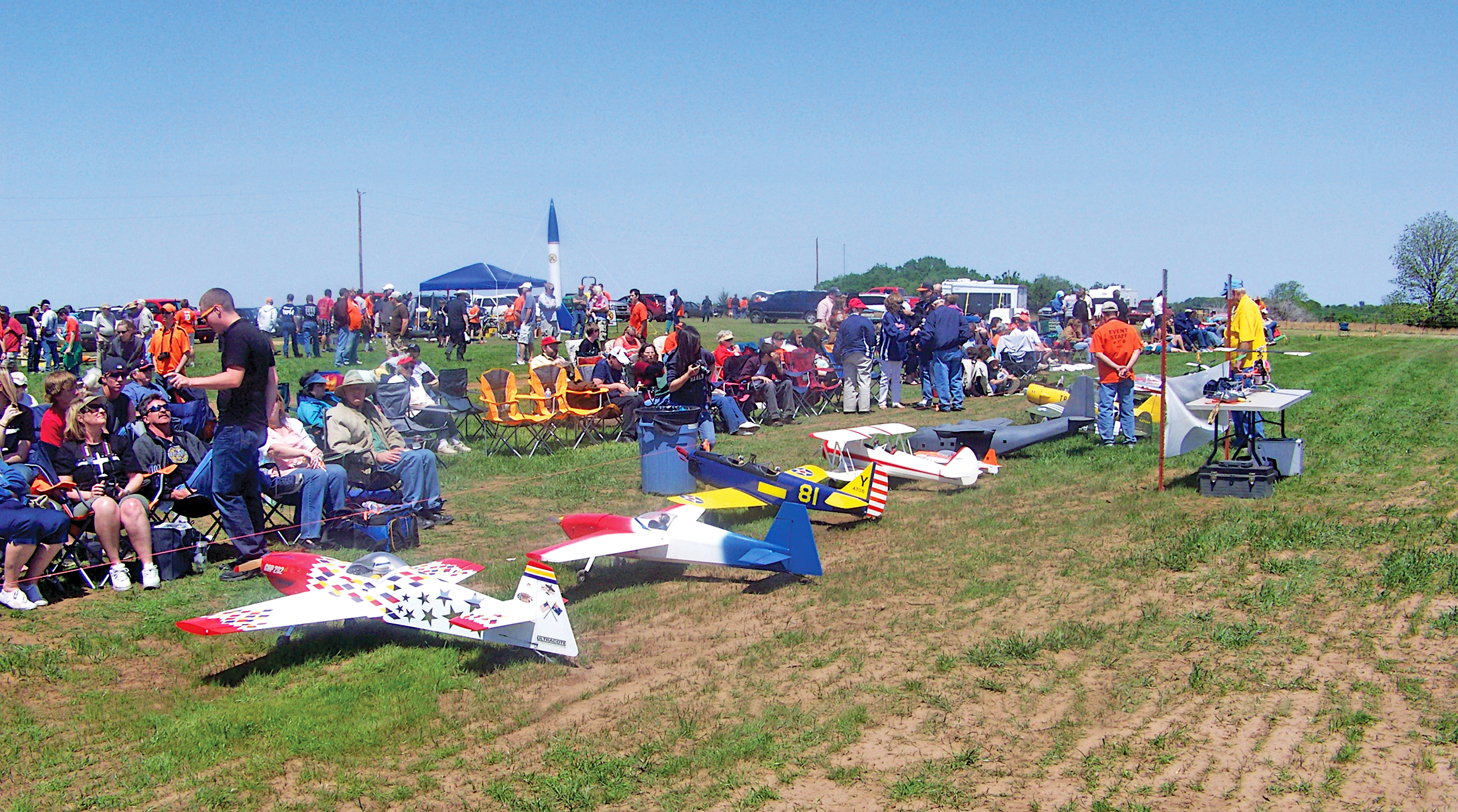 Model airplanes displayed in a field with a crowd in the background.