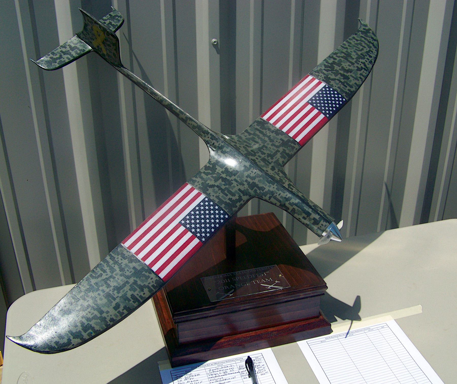 Camouflage drone with American flags on wings, displayed on a table.