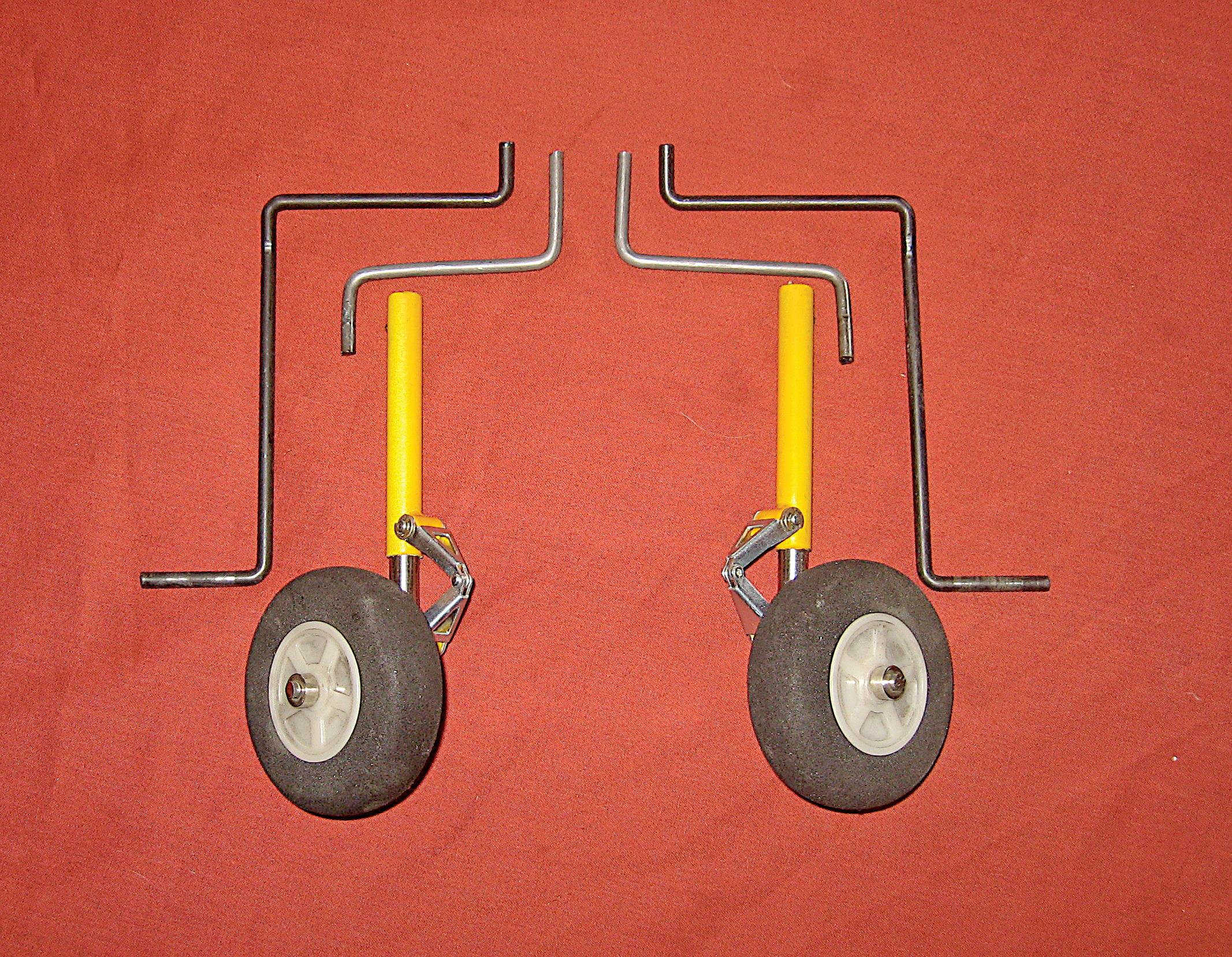 Two model airplane landing gears on a red background.