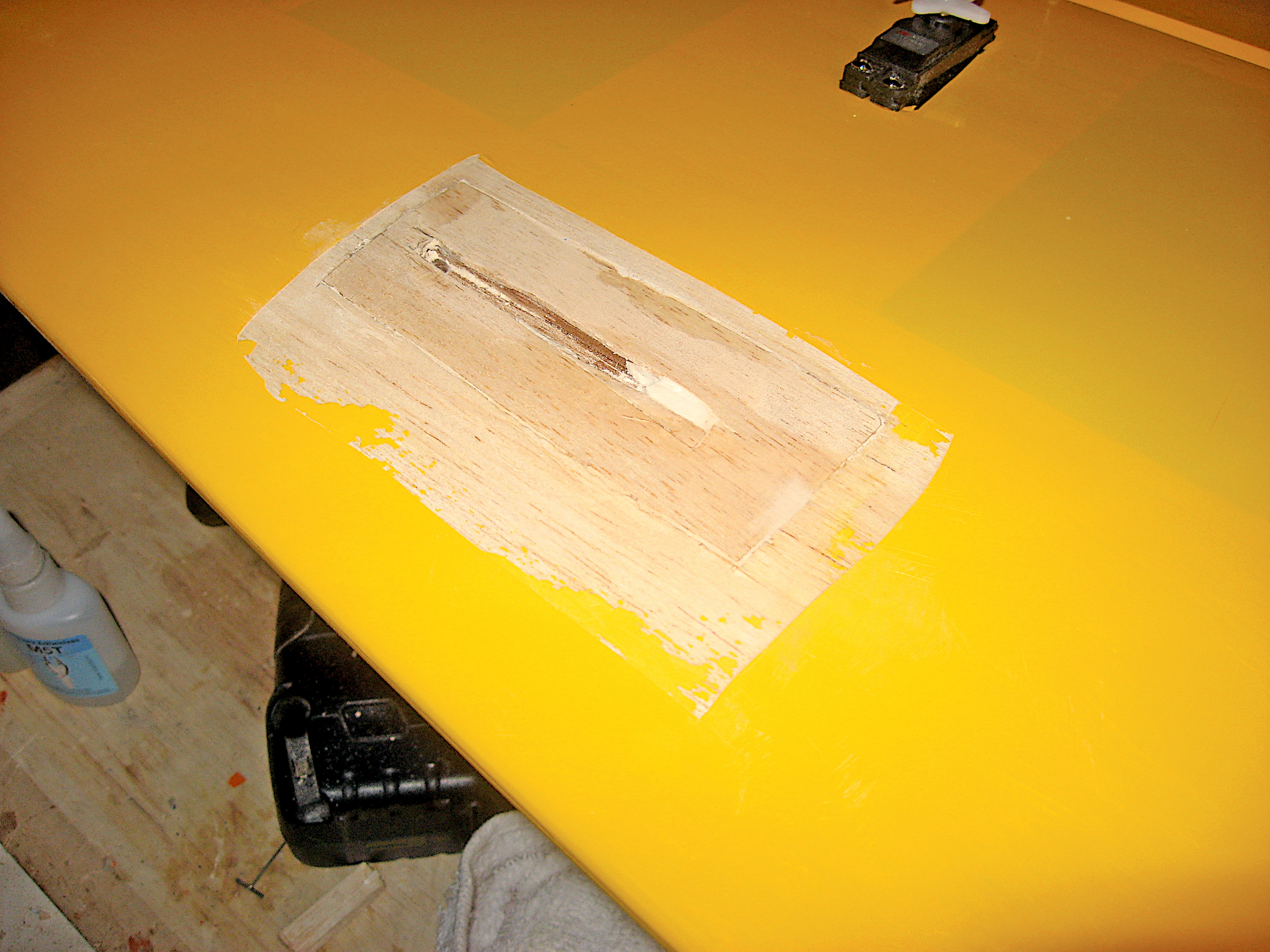 Yellow table with a patch of wood filler, tools in the background.