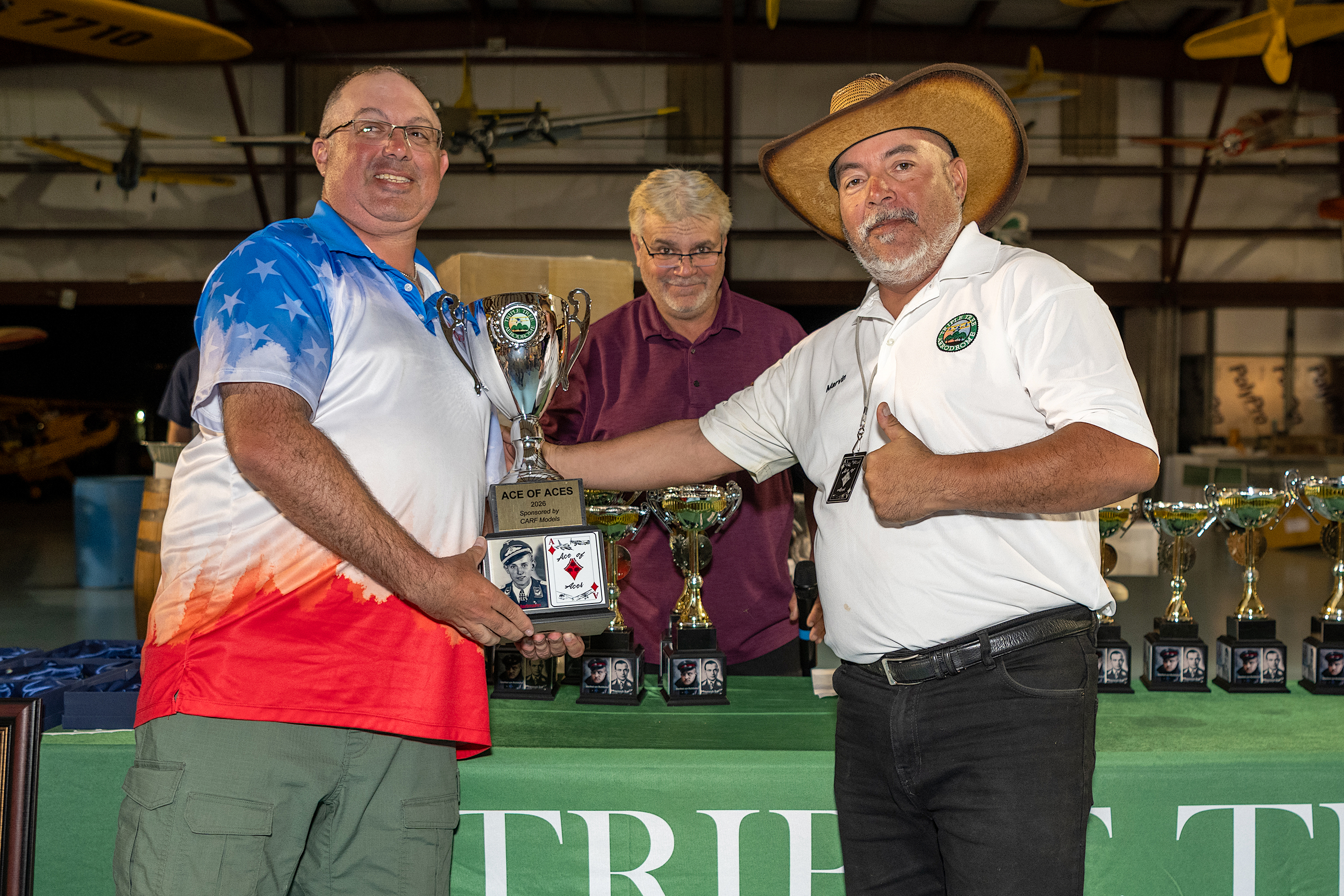 The overall Ace of Aces winner, Dan Landis (L), receives the award from Marvin Alvarez (R). CD Curtis Switzer is in the background. 