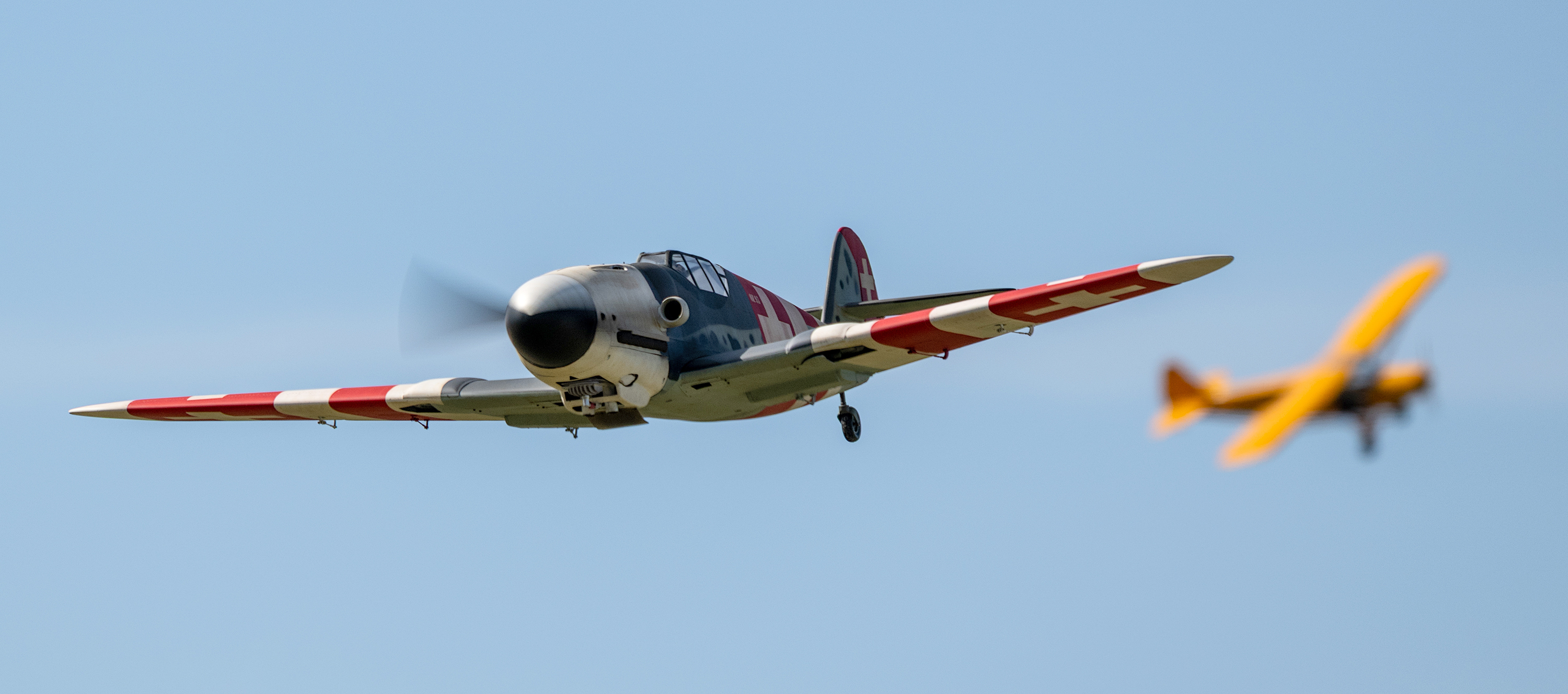 Two vintage planes flying against a blue sky.