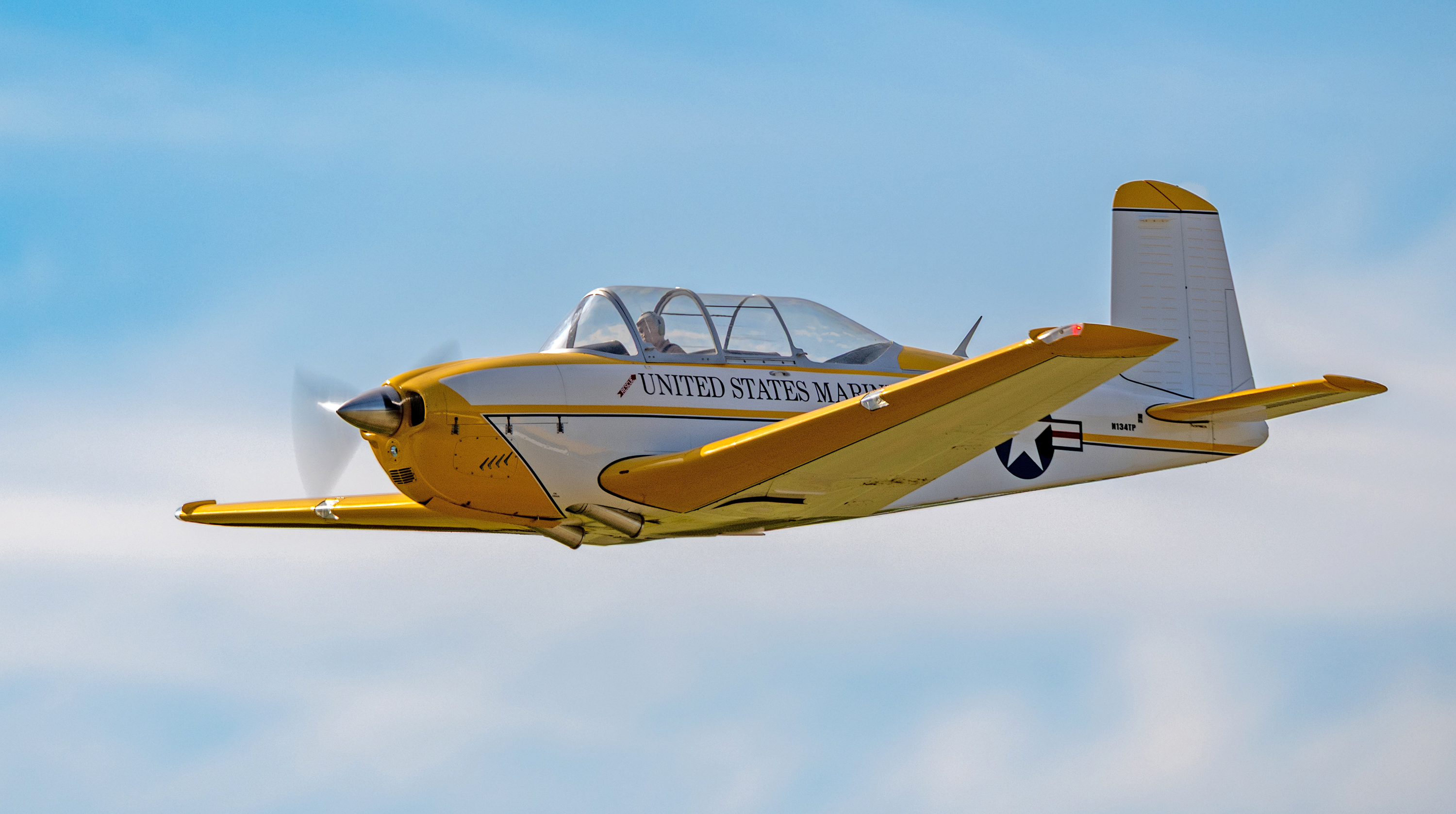 Yellow propeller airplane with blue sky background.