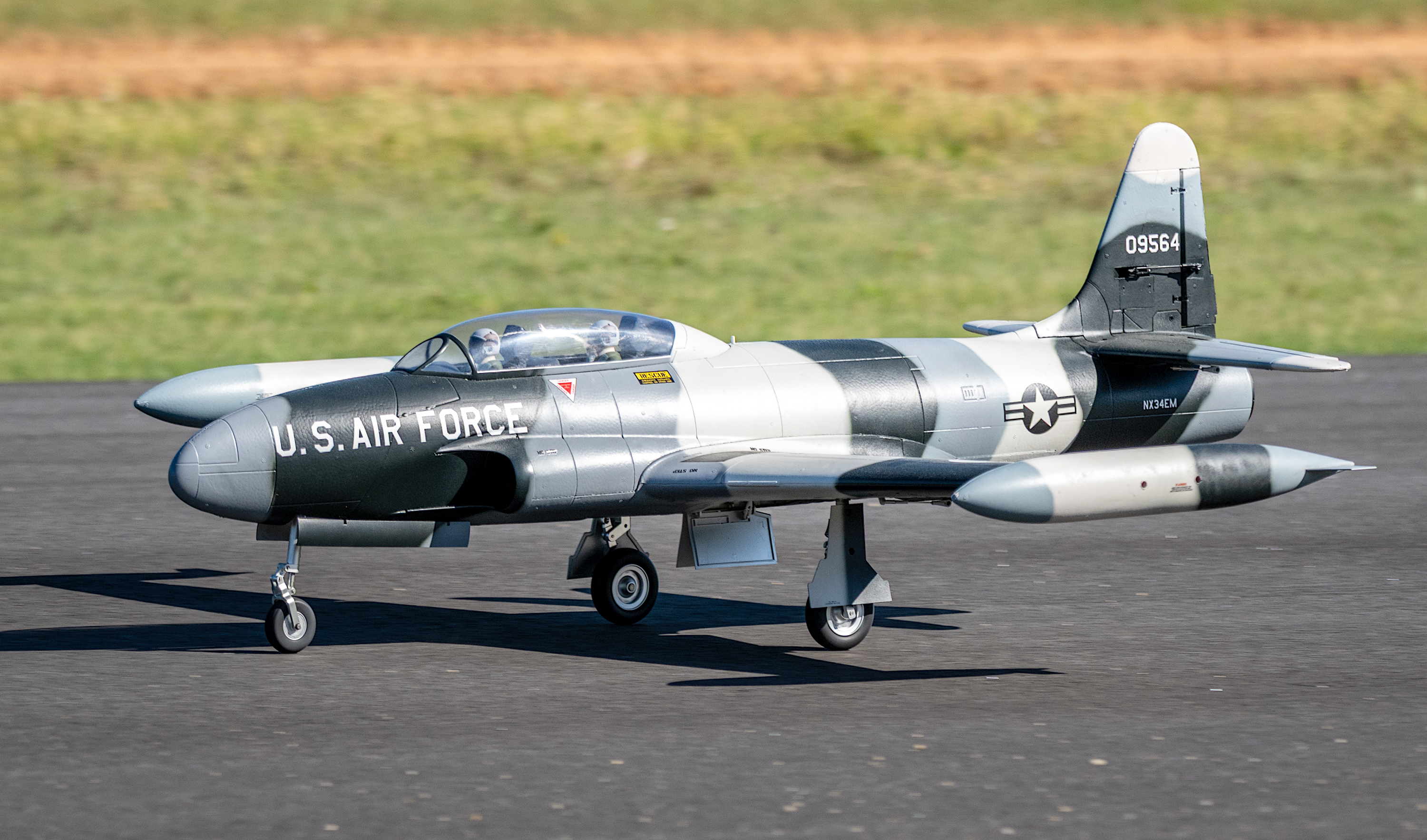 Model jet with "U.S. Air Force" markings on a runway, grass in the background.