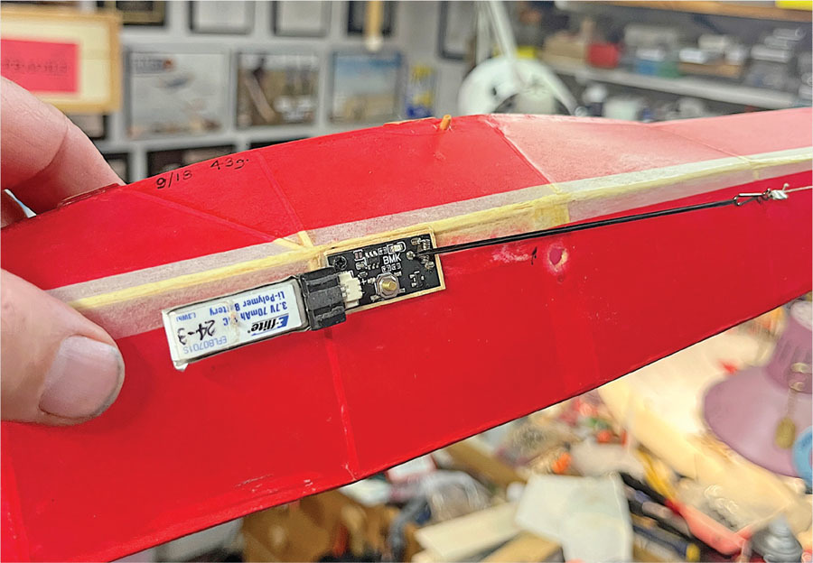 Red model airplane wing with electronic components.