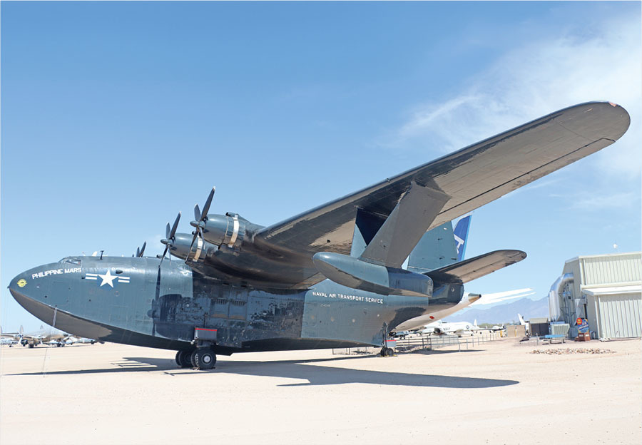 Large military aircraft on desert tarmac under clear blue sky.