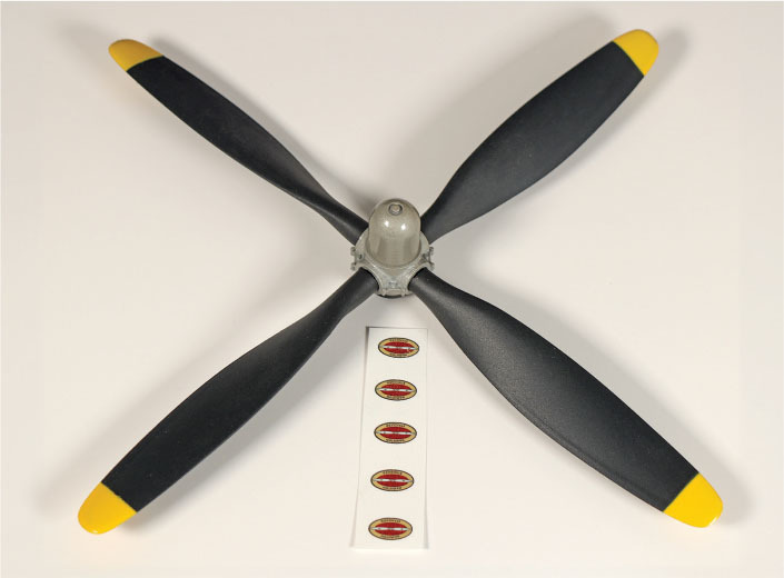 Black four-blade propeller with yellow tips, five red oval logos below.