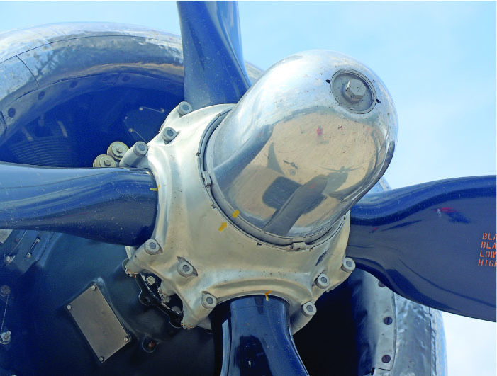 Close-up of a polished airplane propeller against a blue sky.