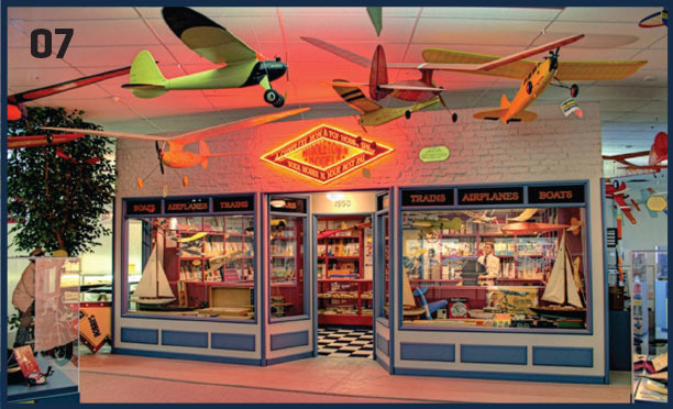 Toy store with model airplanes, ship models, and a neon glow sign above the entrance.