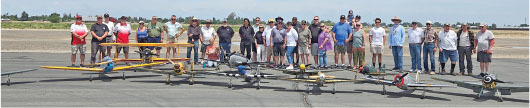 A group of people with model airplanes on a runway.
