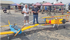 Two men with remote-controlled model planes on a tarmac.
