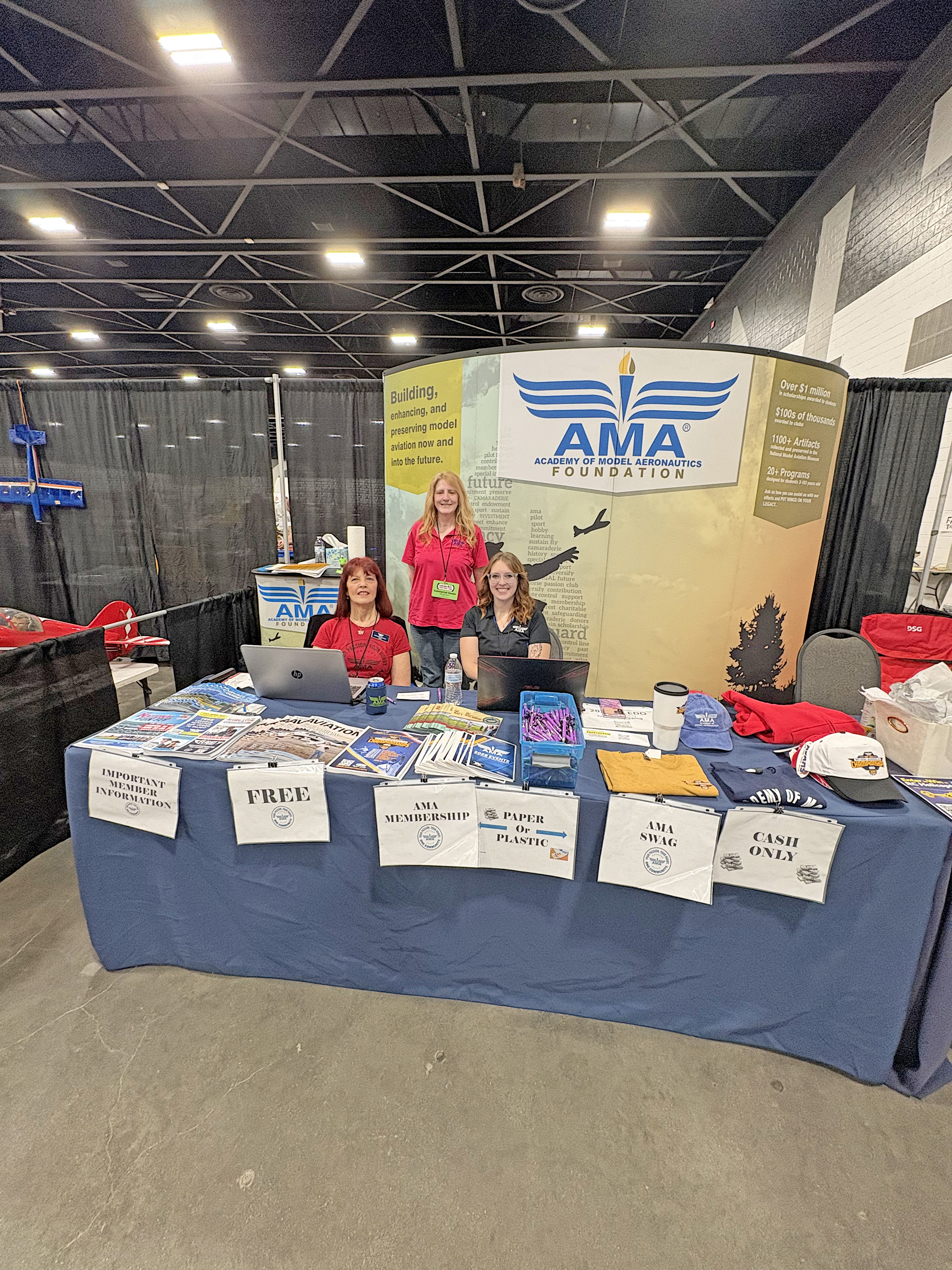 AMA booth with three people, brochures, and signs in an exhibition hall.