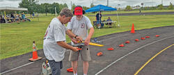 Two men on a track assembling a model aircraft outdoors.