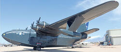 Large, vintage aircraft on display under clear blue sky.