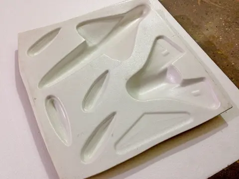 Plastic packaging tray with various shaped cavities.