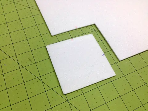 White paper squares on a green grid cutting mat.