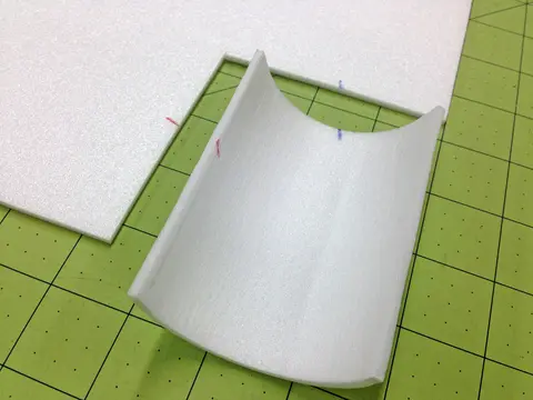 Curved white paper on a green grid cutting mat.