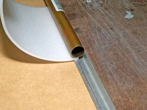 A gold metal tube on a brown surface with translucent sheets.