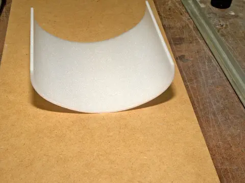 Curved white plastic piece on a wooden surface.