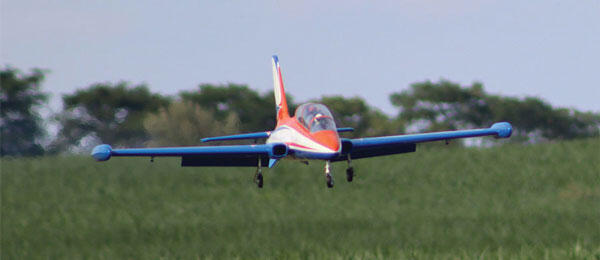 Small red and blue plane flying over a grassy field Hangar 9 Aermacchi MB-339 60-85N ARF Turbine Jet