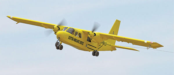 Yellow aircraft with "Skybus" text flying in a clear blue sky.