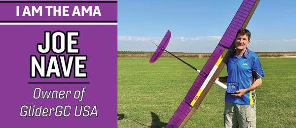 Joe Nave holding a purple glider on a grassy field, blue sky background.