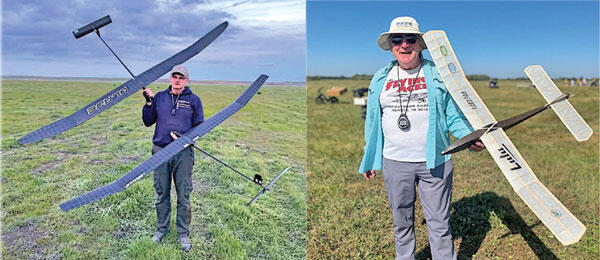 Two people outdoors each holding a model glider plane, one in a blue hoodie and one in a white hat.