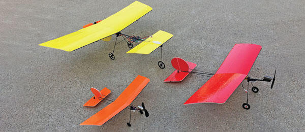 Three colorful model planes on a gray surface.