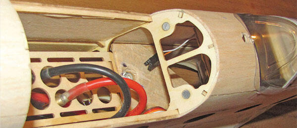 Wooden model airplane interior with wires and compartments.