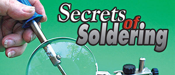 Hand holds soldering iron near lens; text reads "Secrets of Soldering."