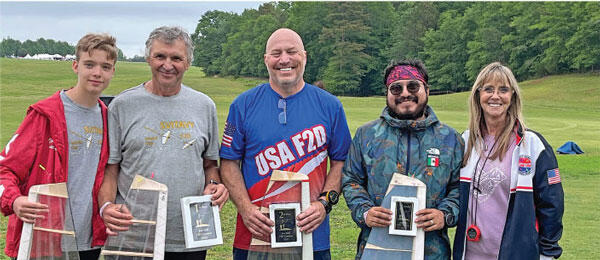 Five people smiling, holding plaques outdoors; one wears a "USA F3D" shirt.
