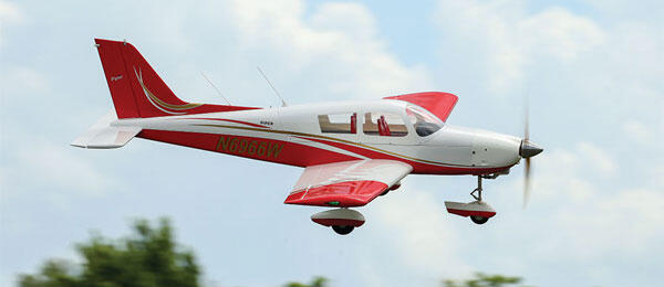 Red and white RC airplane flying in a cloudy sky.
