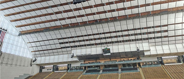 Stadium interior with empty seats and large arched ceiling.