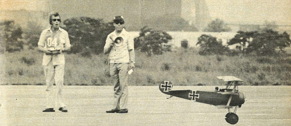 Two people on a runway with a remote-controlled plane.