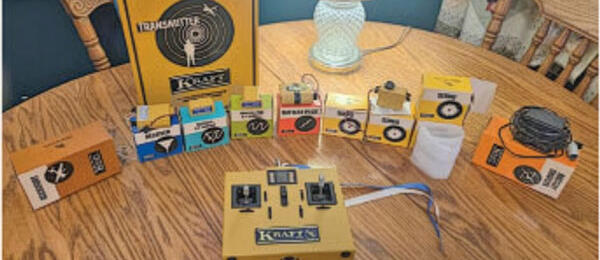 RC Transmitter components on a wooden table with various colored boxes and a lamp.