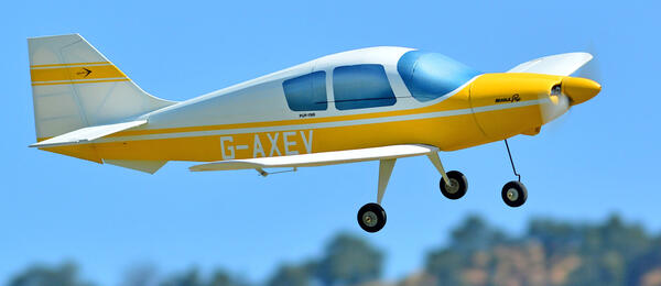Small yellow and white plane mid-flight, blue sky background.