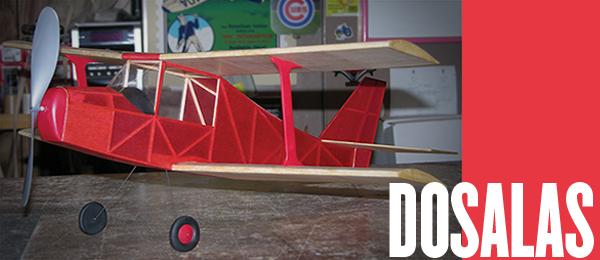 Red model biplane on table, text reads "DOSALAS" on red background.