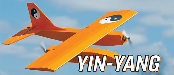 Orange toy plane with yin-yang symbols, flying in a blue sky.