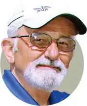 Elderly man with glasses and white beard wearing a white cap and blue shirt.