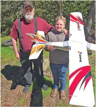 Man and child holding a large model airplane outdoors, smiling.