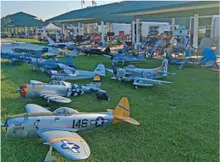 Model airplanes displayed on grass with people in the background.