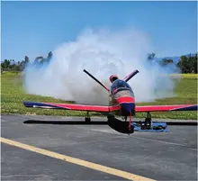 Red and blue RC jet on ground with smoke in the background.